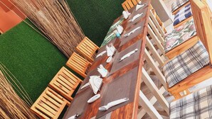 A dining area with a long wooden table set for multiple people, surrounded by wooden chairs with checkered cushions. - Eden Wood Guest House (Shakawe)