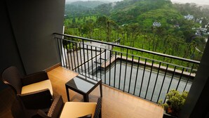 A balcony with wicker furniture and a view of a lush green landscape.