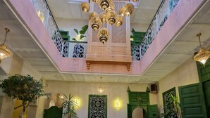 A spacious lobby with a central seating area, a decorative fountain, and a high ceiling with ornate lighting fixtures. - RIAD CONTESSA (Marrakech)