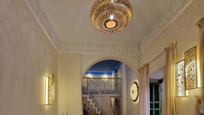 A hotel room with a large bed, a brown sofa, a potted plant, and a decorative ceiling light. - RIAD CONTESSA (Marrakech)