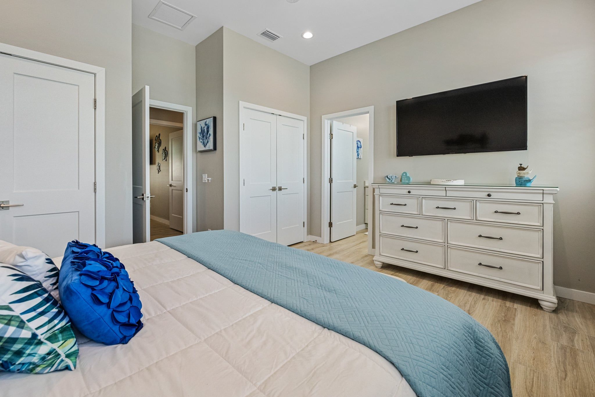 A bedroom with a bed, dresser, and a television on the wall.