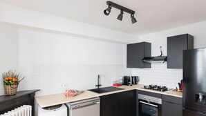 Een moderne keuken met zwarte kastjes, een vaatwasser, een oven en een koelkast.