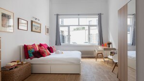Een slaapkamer met een bed, een bureau en een raam.