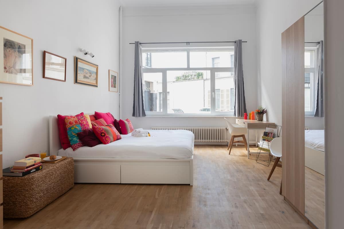 A bedroom with a bed, a desk, and a window.