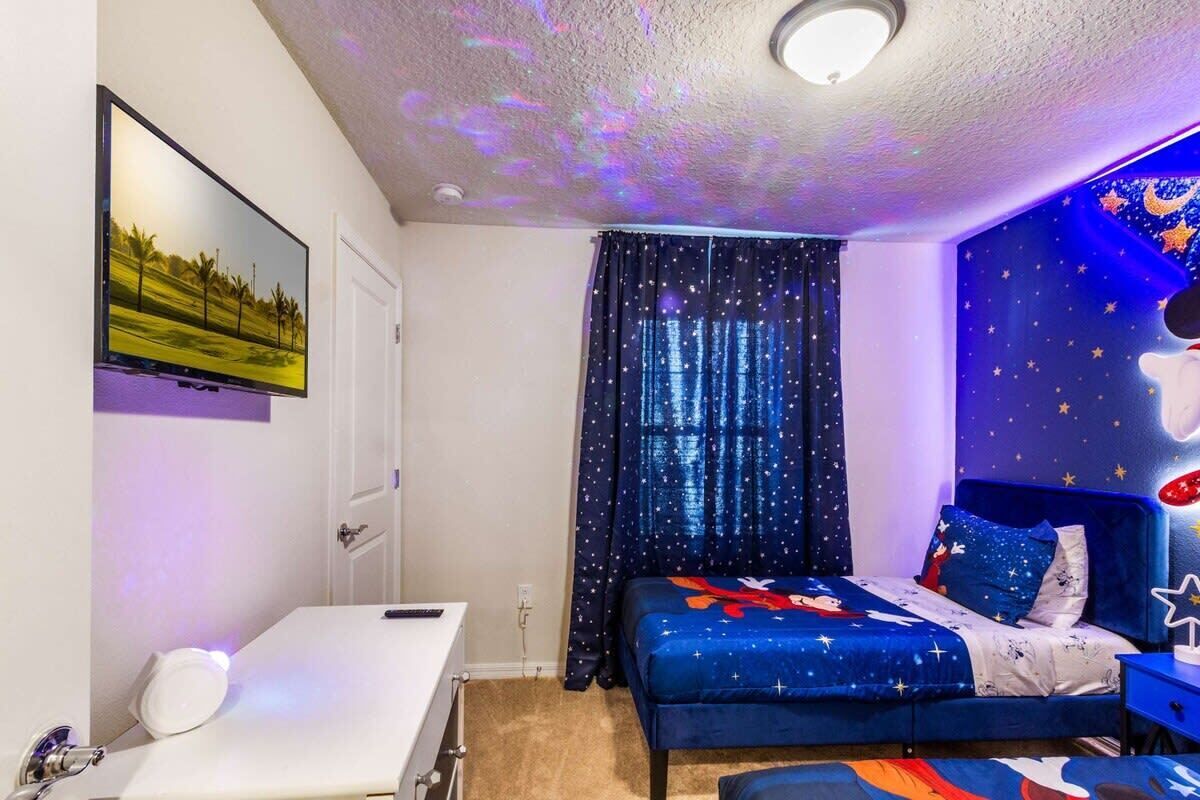 A bedroom with a bed, a desk, and a nightstand.
