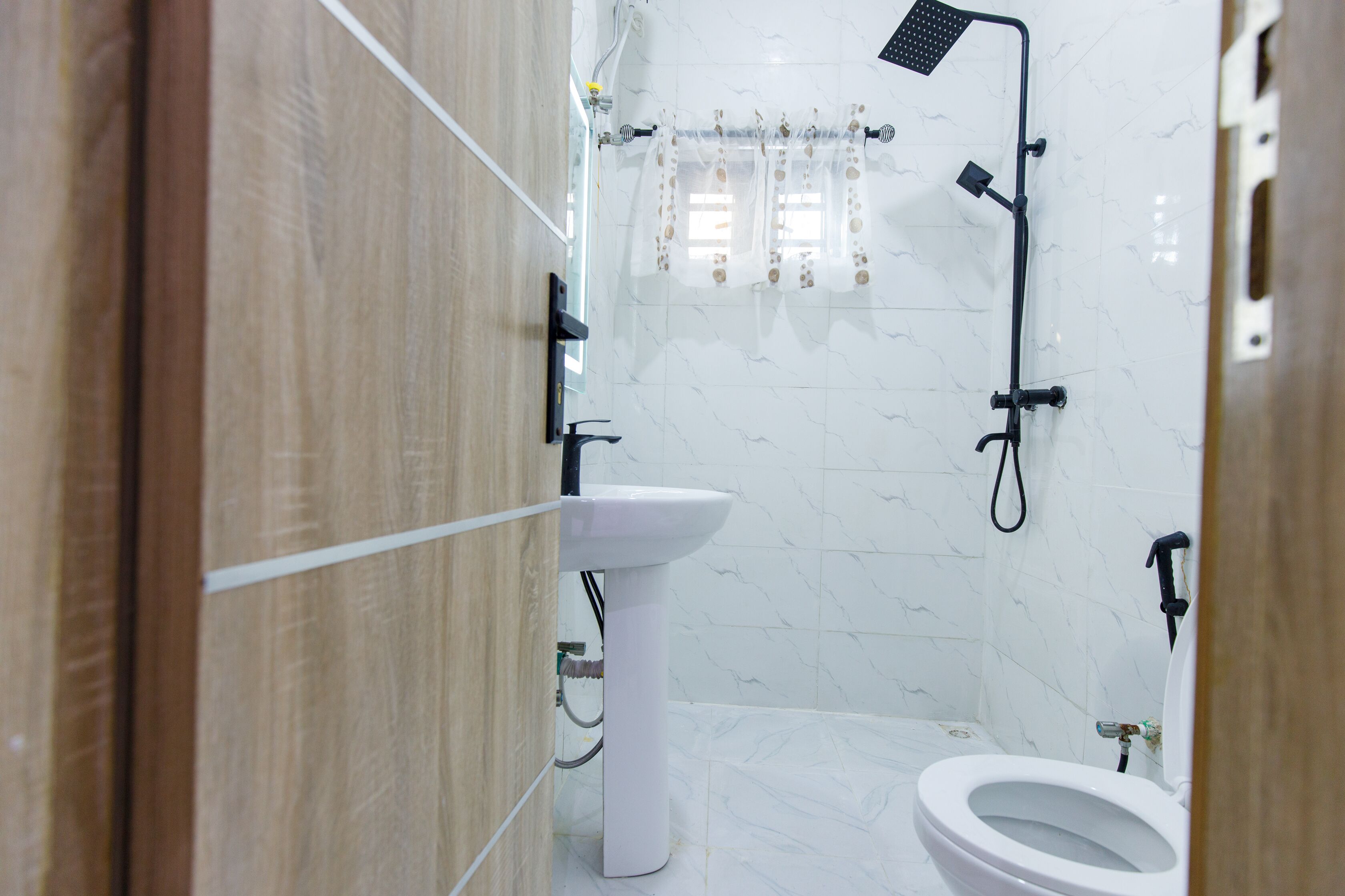 A bathroom with a white sink, toilet, and shower area.