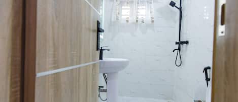 A bathroom with a white sink, toilet, and shower area.