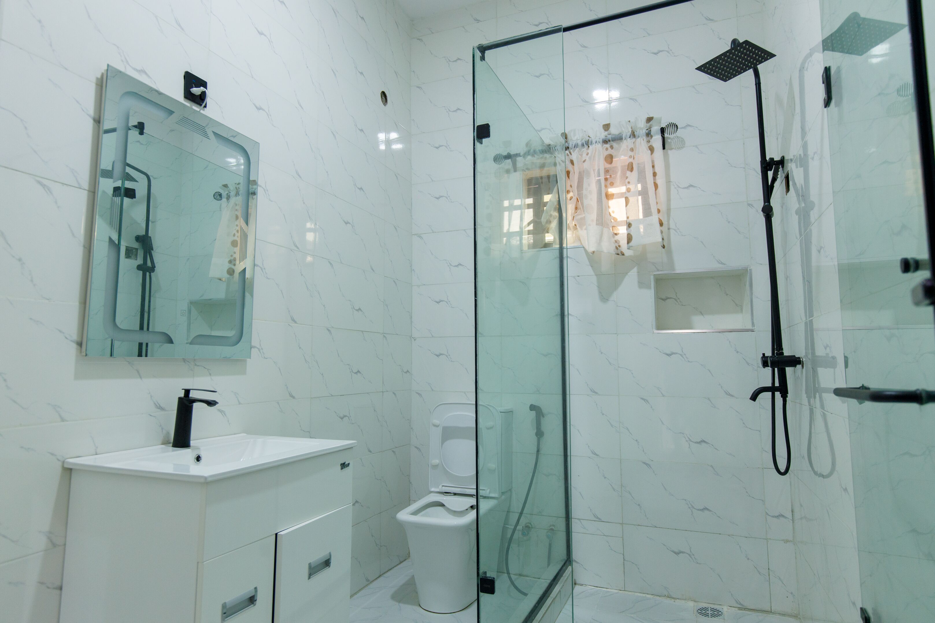 A modern bathroom with a glass-enclosed shower, a white sink, and a toilet.