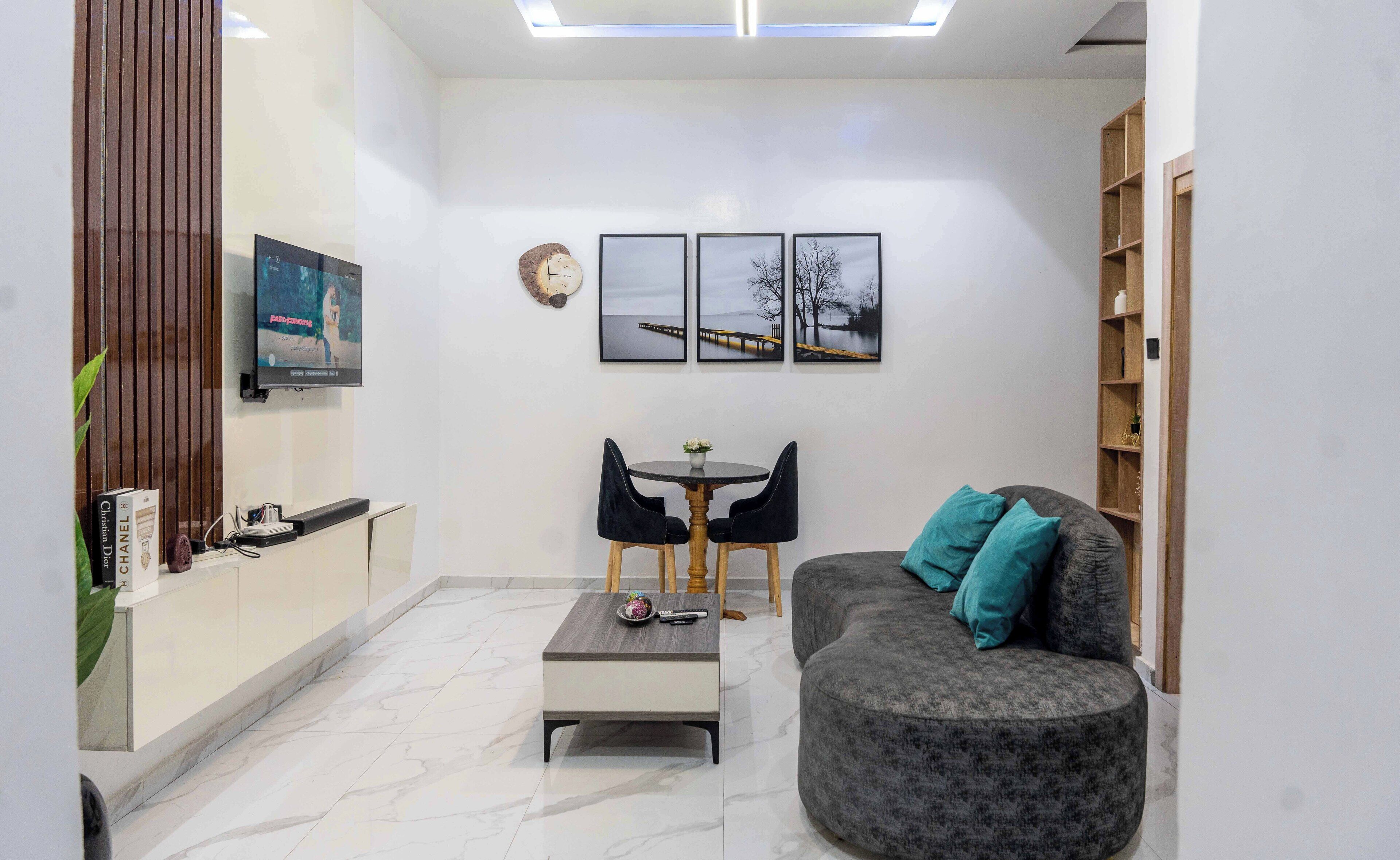 Un salon moderne comprenant un canapé, une table basse, un téléviseur et un coin repas avec des chaises.