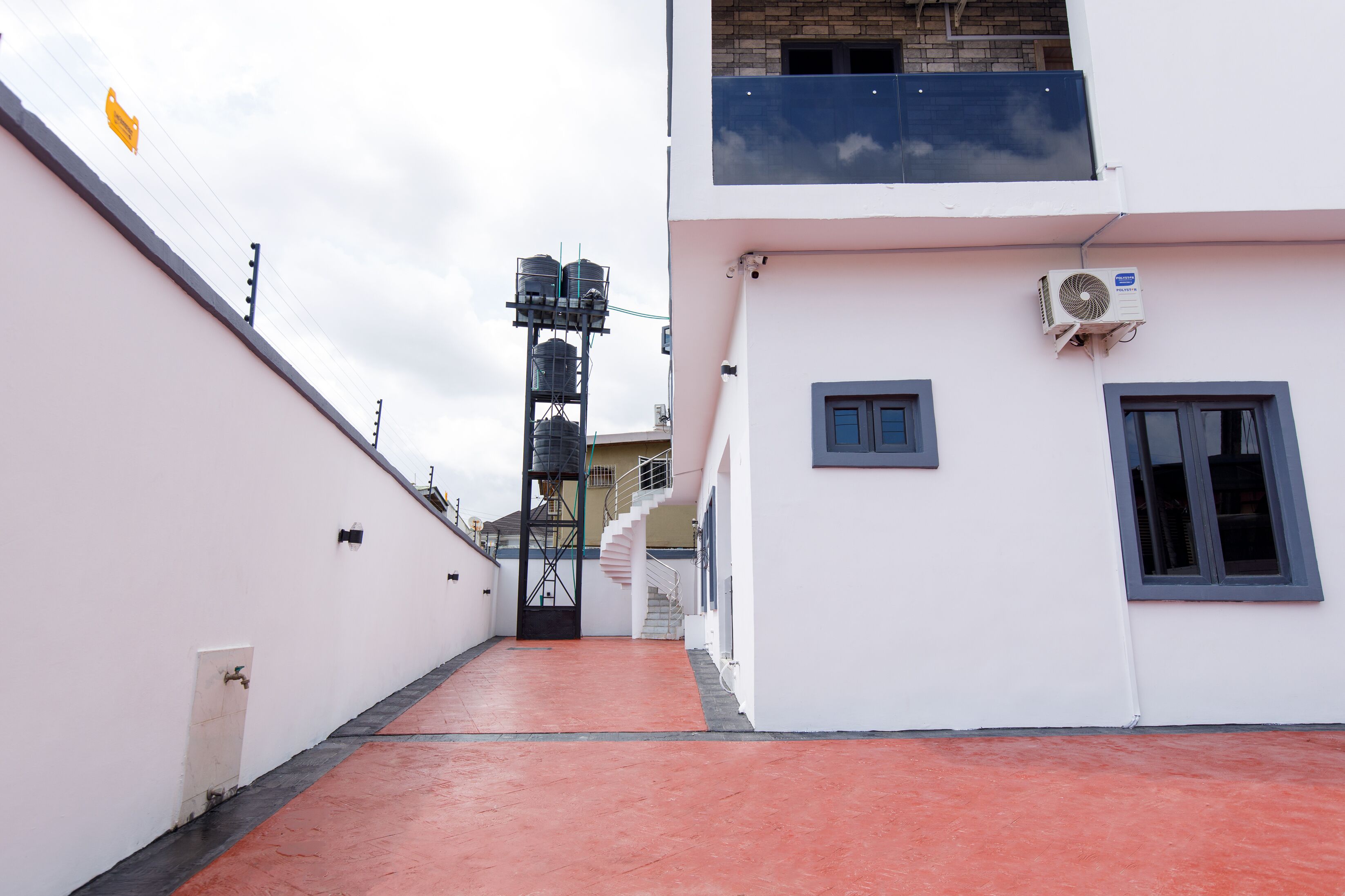A narrow corridor with a red floor leading to a staircase.