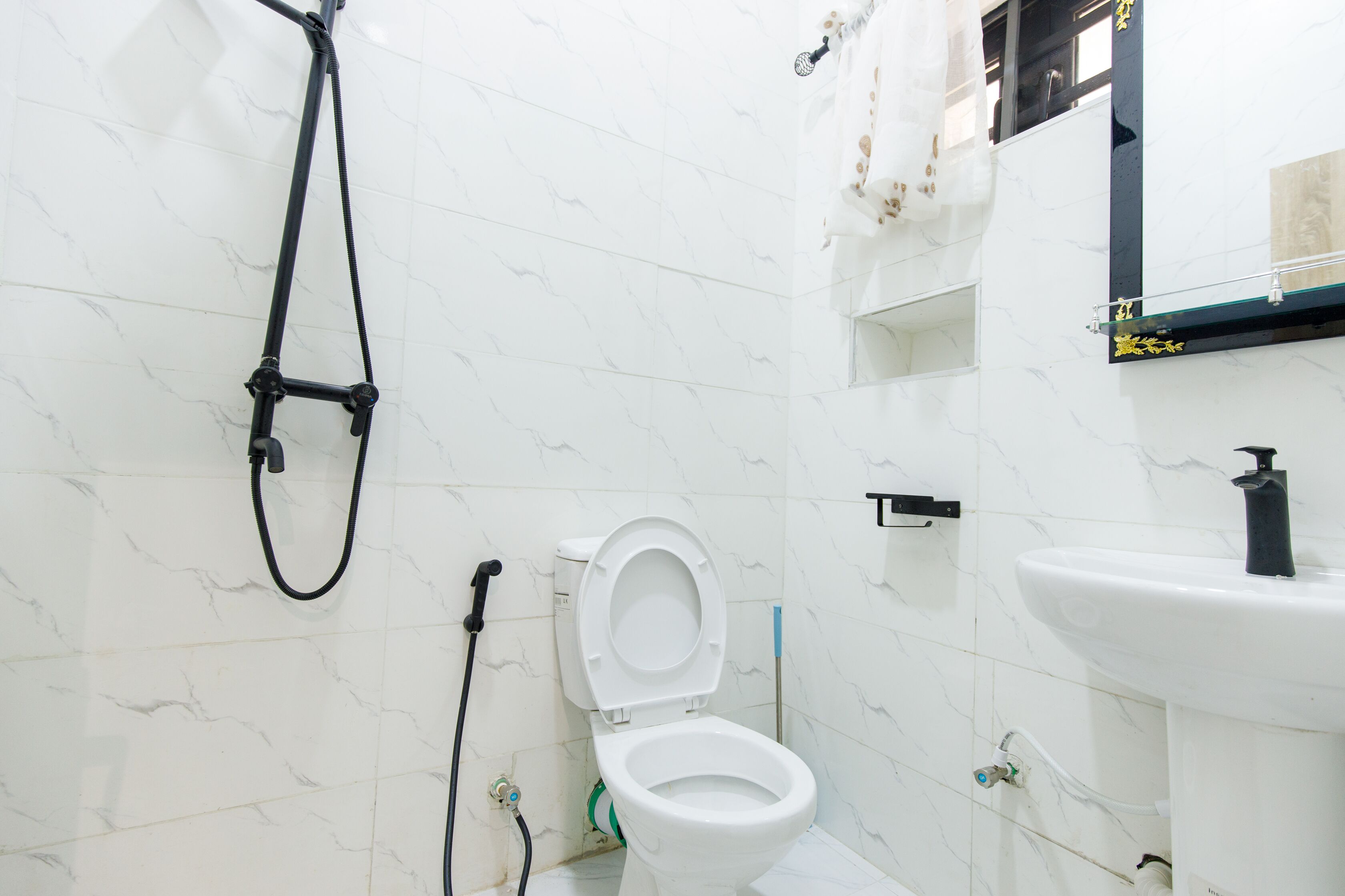 Een badkamer met een wit toilet, douche en wastafel.