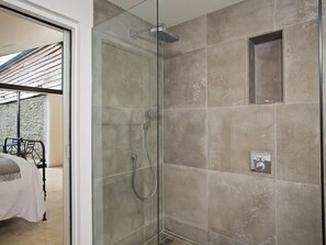 Um chuveiro envidraçado com um chuveiro manual e painel de controle fixado na parede.