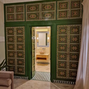 A doorway with intricate green and gold patterns, leading to a bathroom with a tiled floor and a sink. - RIAD CONTESSA, 6 magnificent suites in the best Medina neighborhood, Dar Bacha   (Marrakech)