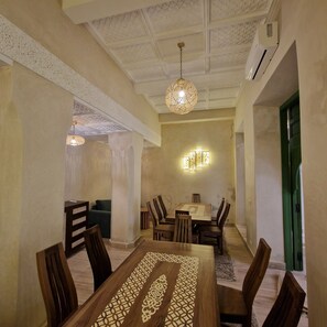 A dining area with a high ceiling, ornate ceiling design, and a chandelier. There are wooden chairs and a table with a decorative inlay. - RIAD CONTESSA, 6 magnificent suites in the best Medina neighborhood, Dar Bacha   (Marrakech)