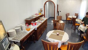 A dining area with multiple tables and chairs, a buffet setup with various food items, and a coffee machine. - House Quattro Mori (Rome)