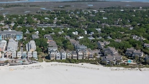Une vue aérienne d’une plage, avec une rangée de maisons et un grand bâtiment doté d’une piscine.