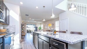 A modern kitchen with granite countertops, stainless steel appliances, and pendant lighting. - 6BR Villa w/Theater & Pool near Disney (Davenport)