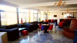 A spacious lobby with a seating area, a dining table, and a chandelier. - Angle Atlas Hotel (Dir El Ksiba)