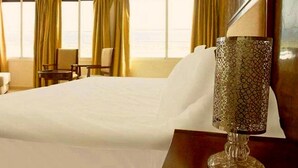 A hotel room with a large bed, a bedside lamp, and a view of the sea through the windows. - Angle Atlas Hotel (Dir El Ksiba)