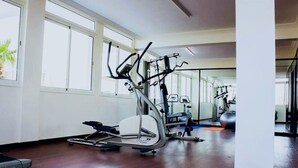 A spacious gym with cardio machines, a rowing machine, and a stationary bike. - Angle Atlas Hotel (Dir El Ksiba)