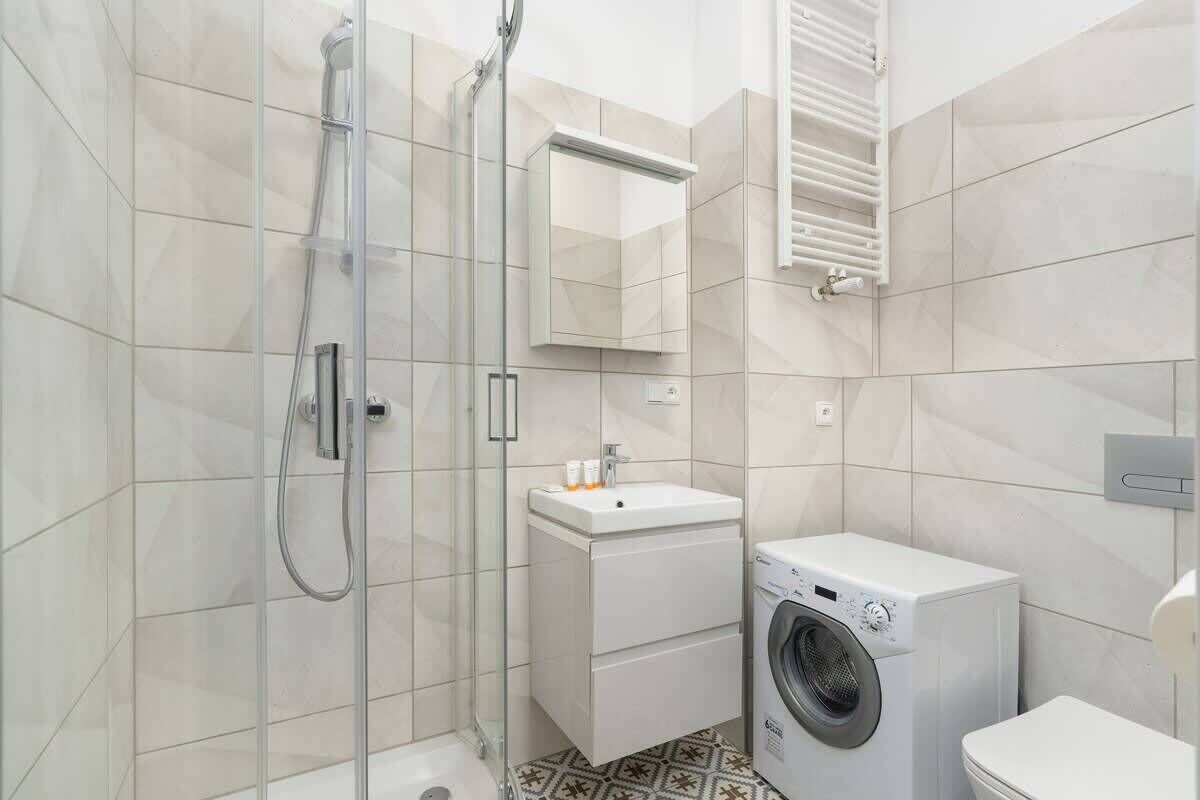 Une salle de bain moderne avec une douche à parois de verre, un lavabo intégré, un lave-linge et des toilettes.