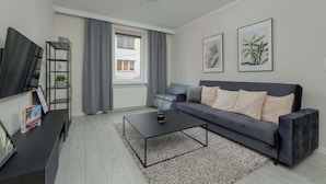A modern living room with a grey sofa, a black coffee table, and framed artwork on the wall.