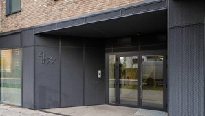 Entrada de um edifício moderno com fachada metálica, portas de vidro e um letreiro com o número 1.
