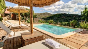 A poolside area with wooden deck, lounge chairs, and a thatched umbrella. - Son Cladera Bosch by Rentallorca (Manacor)