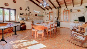 A spacious kitchen with a dining area, featuring a tiled floor, wooden furniture, and a ceiling with exposed beams. - Son Cladera Bosch by Rentallorca (Manacor)