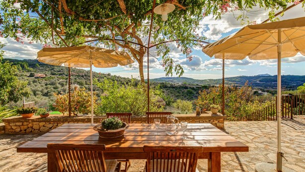 An outdoor patio with a wooden table and chairs, surrounded by stone walls and potted plants. - Son Cladera Bosch by Rentallorca (Manacor)