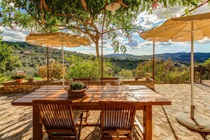 An outdoor patio with a wooden table and chairs, surrounded by stone walls and potted plants. - Son Cladera Bosch by Rentallorca (Manacor)