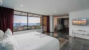 A hotel room with a large bed, a TV, and a balcony with a view of the sea. - LAYAN Hotel & Spa (Quepos)