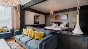 A modern hotel room with a blue sofa, a bed, a large mirror, and a chandelier. - LAYAN Hotel & Spa (Quepos)