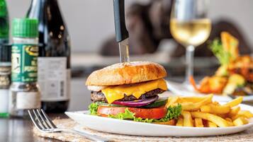Une assiette avec un hamburger, des frites et un verre de vin blanc, posée sur une table.