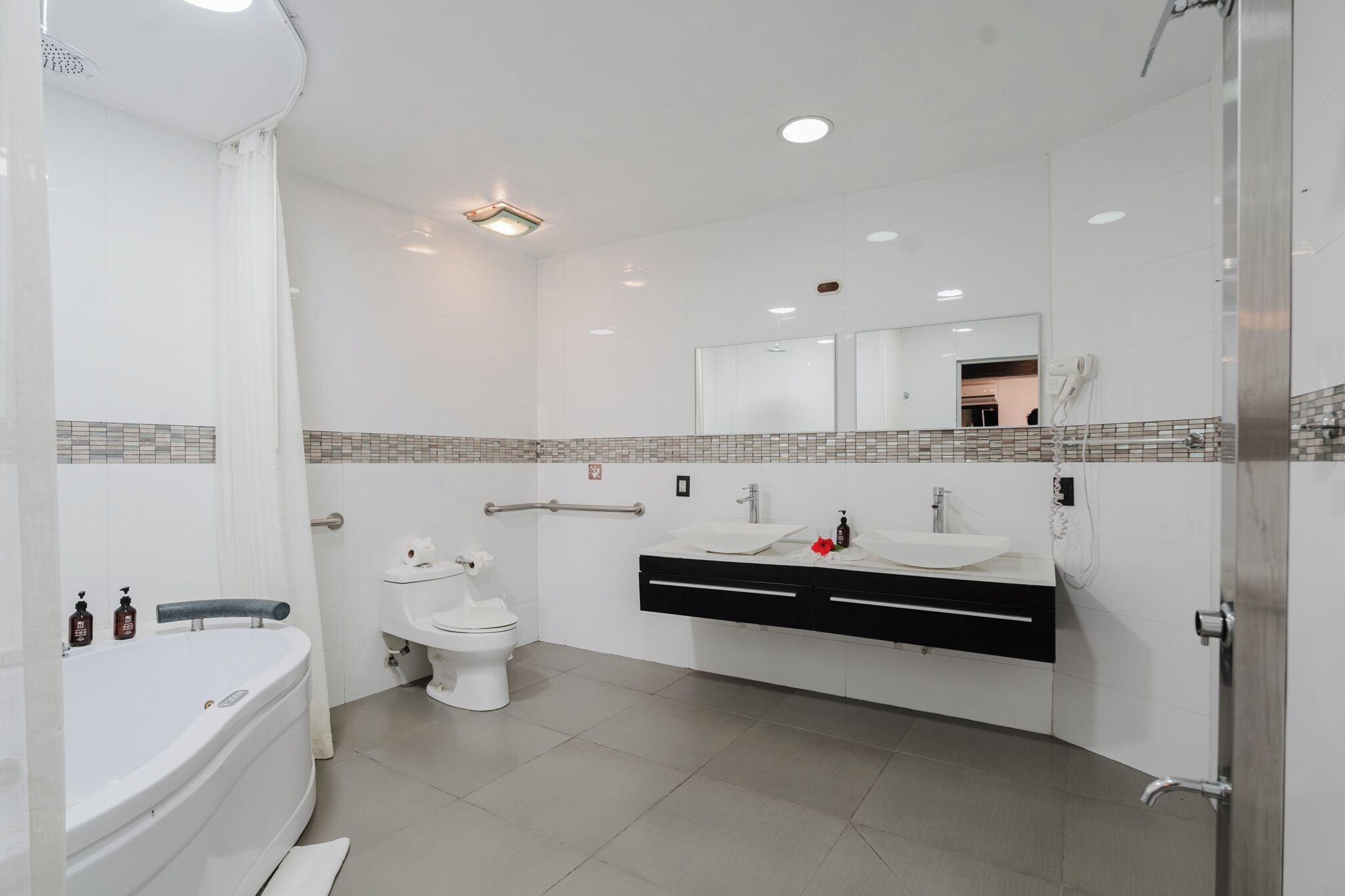 A modern bathroom with a bathtub, toilet, and vanity with a mirror.