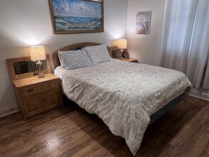 Ein Schlafzimmer mit einem Bett, zwei Nachttischen, einem Holzschrank und einem Bild an der Wand.