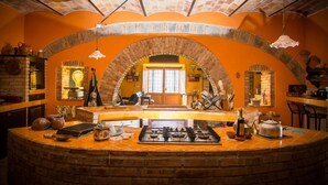 Una cocina con isla central, arco de ladrillo y lámparas colgantes.