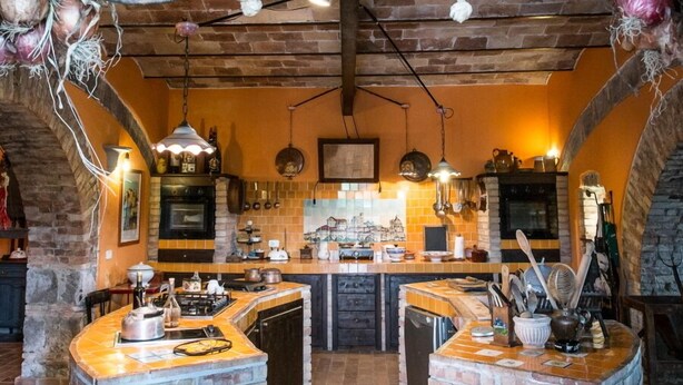Una cocina rústica con paredes de ladrillo visto, salpicadero de azulejos y lámparas colgantes.