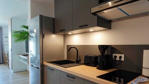 A modern kitchen with a built-in refrigerator, a stove, a coffee maker, and a sink. - Beautiful studio on the beachfront Baie Orientale (Saint-Martin)