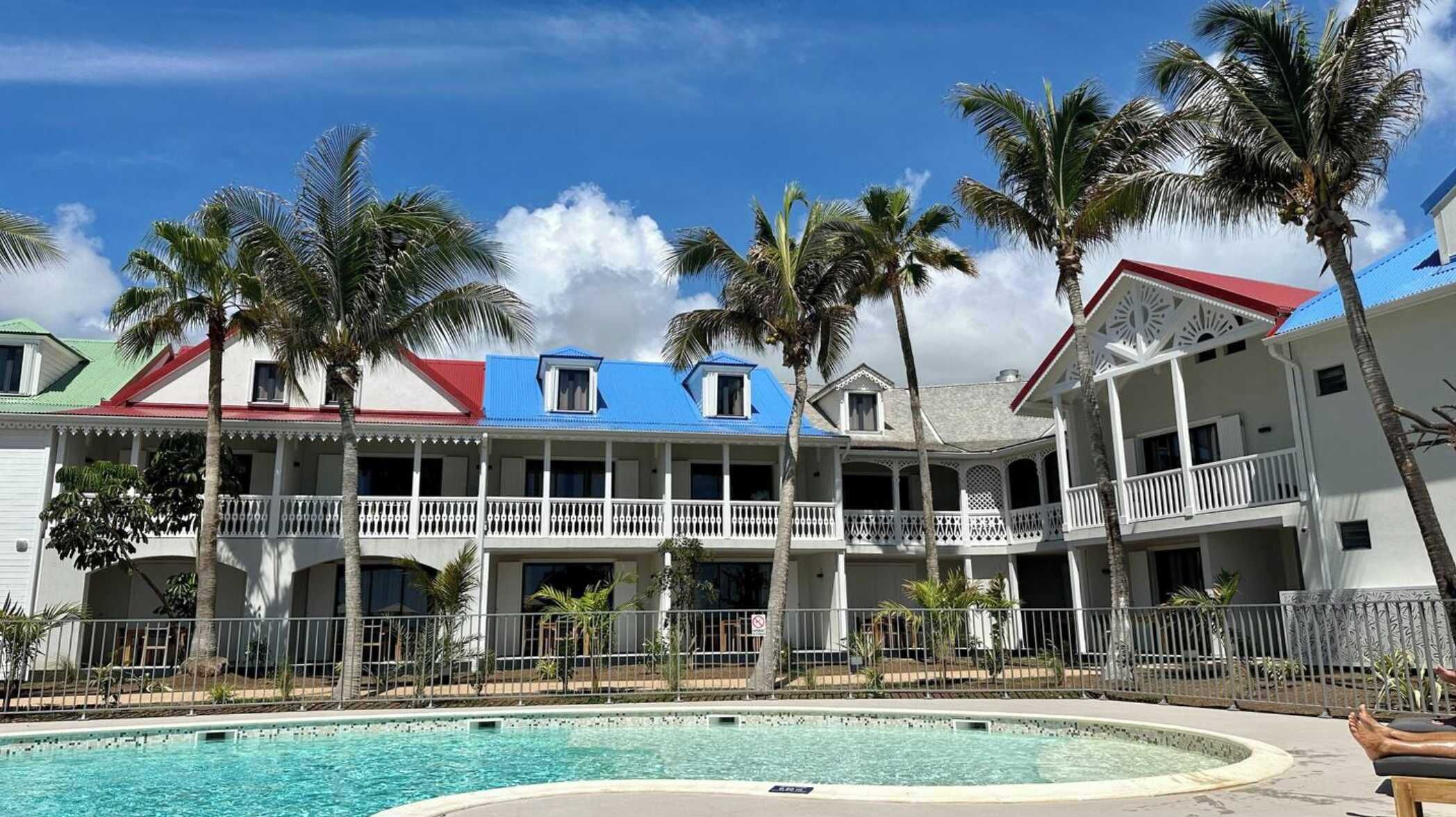 A resort with a pool, multiple balconies, and palm trees.