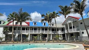 A resort with a pool, multiple balconies, and palm trees.