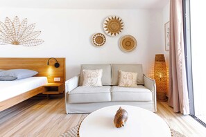 A modern bedroom with a wooden bed, a grey sofa, and a round coffee table.