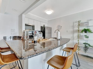 Your modern kitchen features gleaming granite countertops, full-size stainless appliances, and a breakfast bar with leather seating—perfect for cooking and sharing meals together.