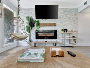 Settle into your stylish living space where modern design meets cozy comfort. The whitewashed brick wall, electric fireplace, and hanging chair create a relaxing retreat perfect for unwinding after exploring the area.