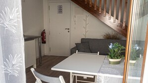 Een kamer met een witte tafel, een grijze bank, een houten trap en een deur waarop 'SALIDA' staat.
