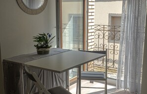 Een balkon met een tafel en stoelen, een bloempot en een sierhek van metaal.
