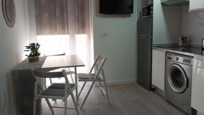 Een compacte keuken met een eethoek, een wasmachine en een flatscreen-televisie.