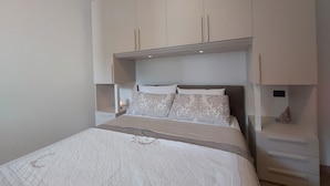 Ein Schlafzimmer mit einem Bett, Nachttischen und integrierten Schränken.