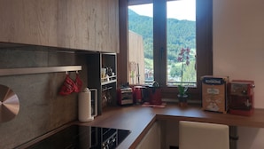 Eine moderne Küche mit einem großen Fenster, einem Herd und einer Kaffeemaschine.