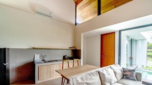 Una cocina moderna con comedor, un sofá y un ventanal corredera que da a un balcón.
